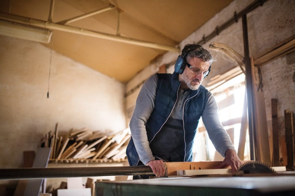 A man worker in the carpentry workshop, working with wood.